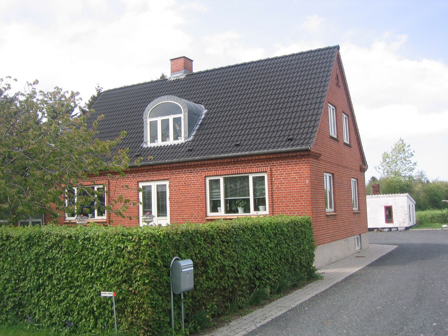 Rødstenshus med sort tegltag og kvist