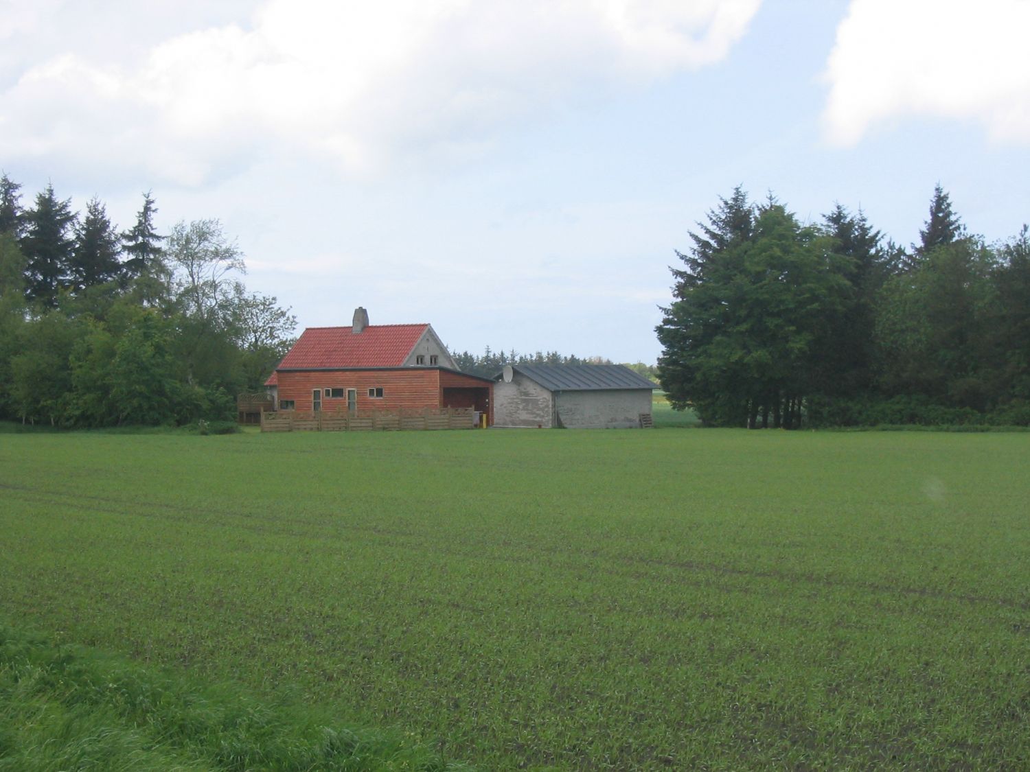 Landejendom med rødt tag set over marken