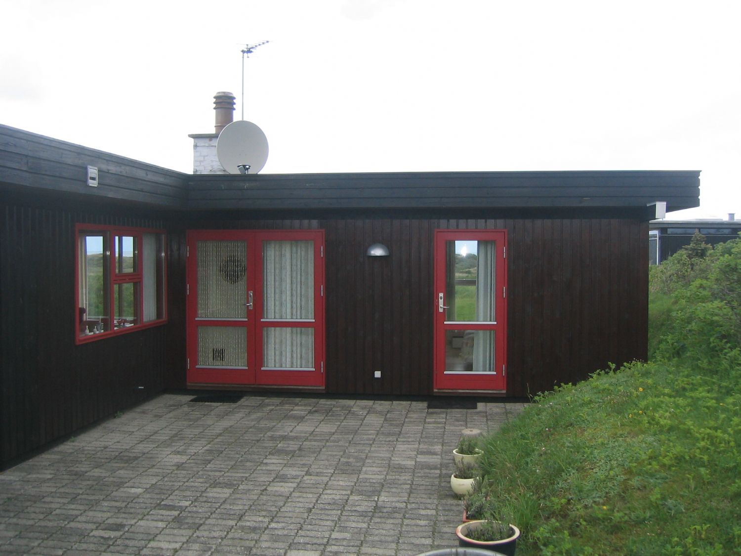 Sommerhus i sort træ med røde vinduer og døre